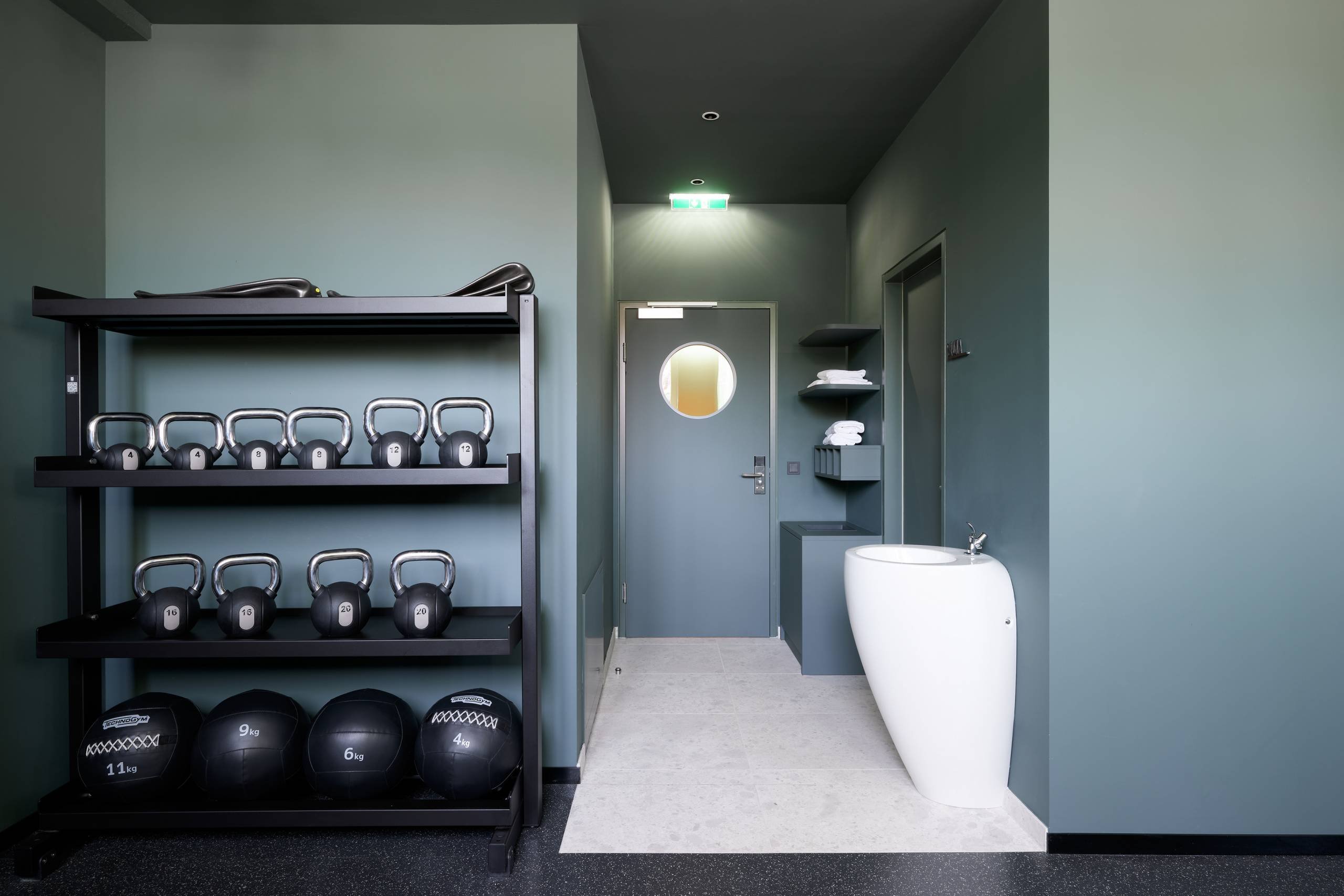 hotel gym with floorstanding washbasin, weights and dark green walls