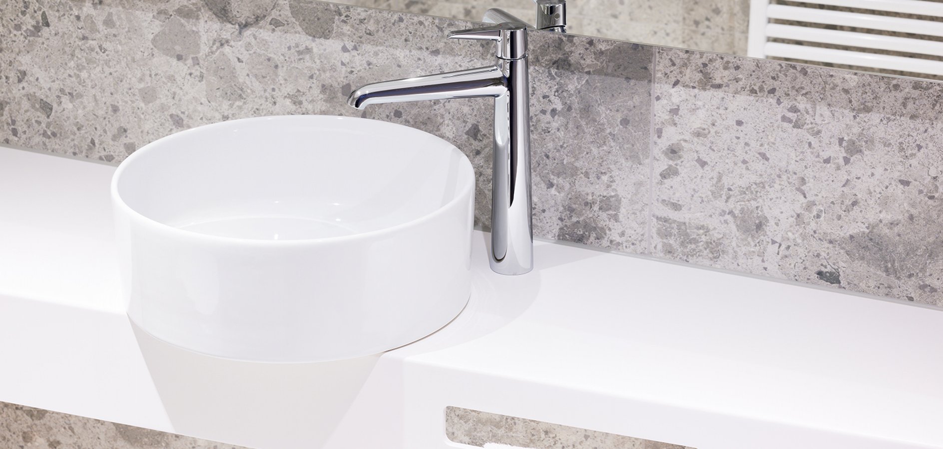 round white washbasin with bespoke countertop and chrome faucet in a hotel