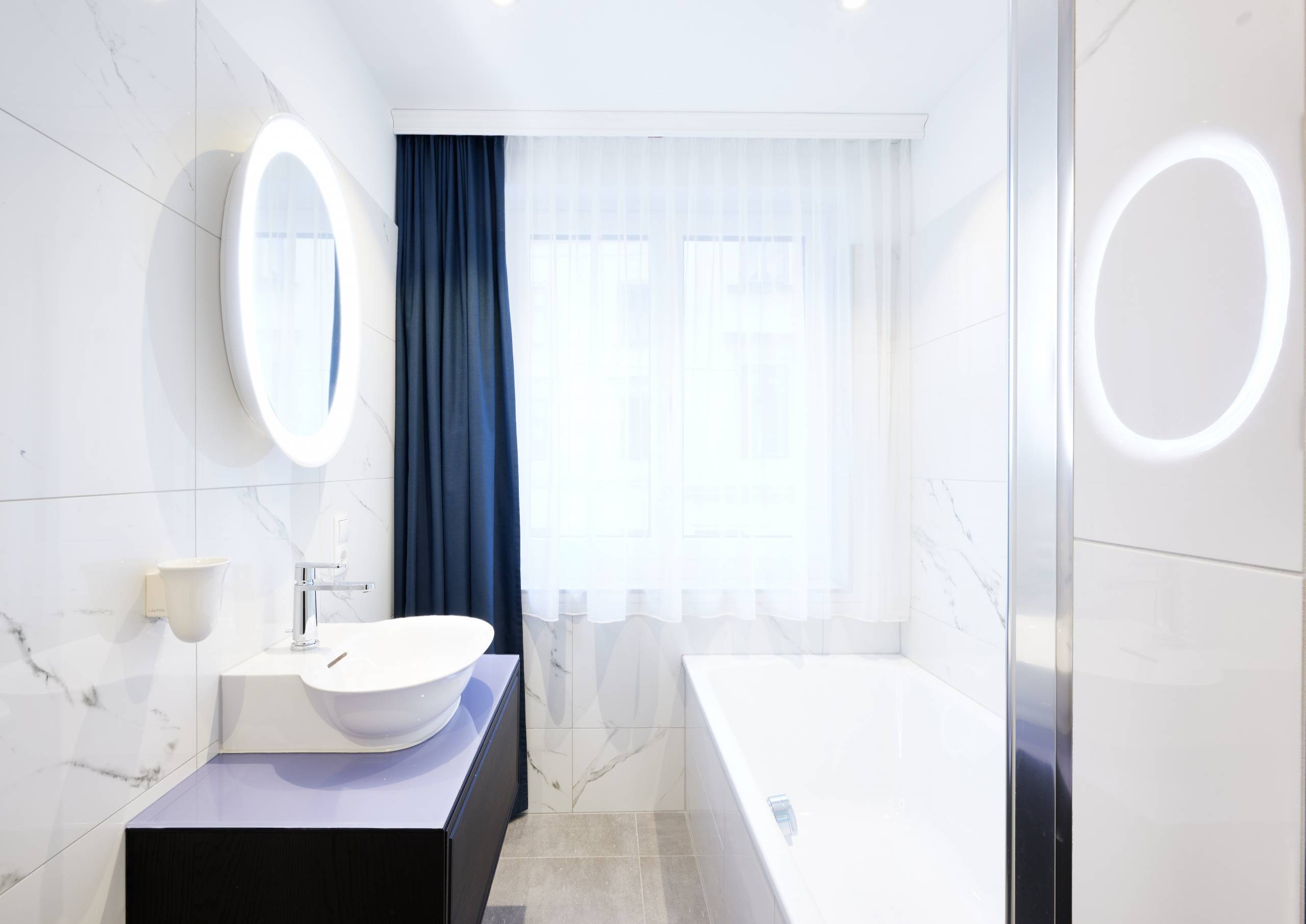 lichtdurchflutetes Badezimmer mit weißer Keramik und dunkelblauen Akzenten