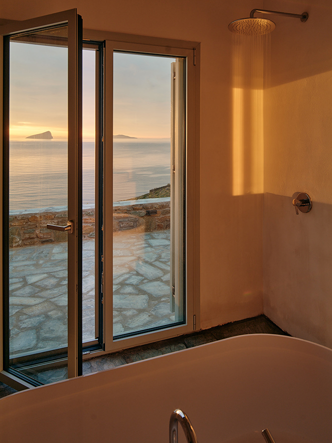 Weiße Badewanne, Fenster mit Blick auf Meer, Sonnenuntergang, Duschenarmatur