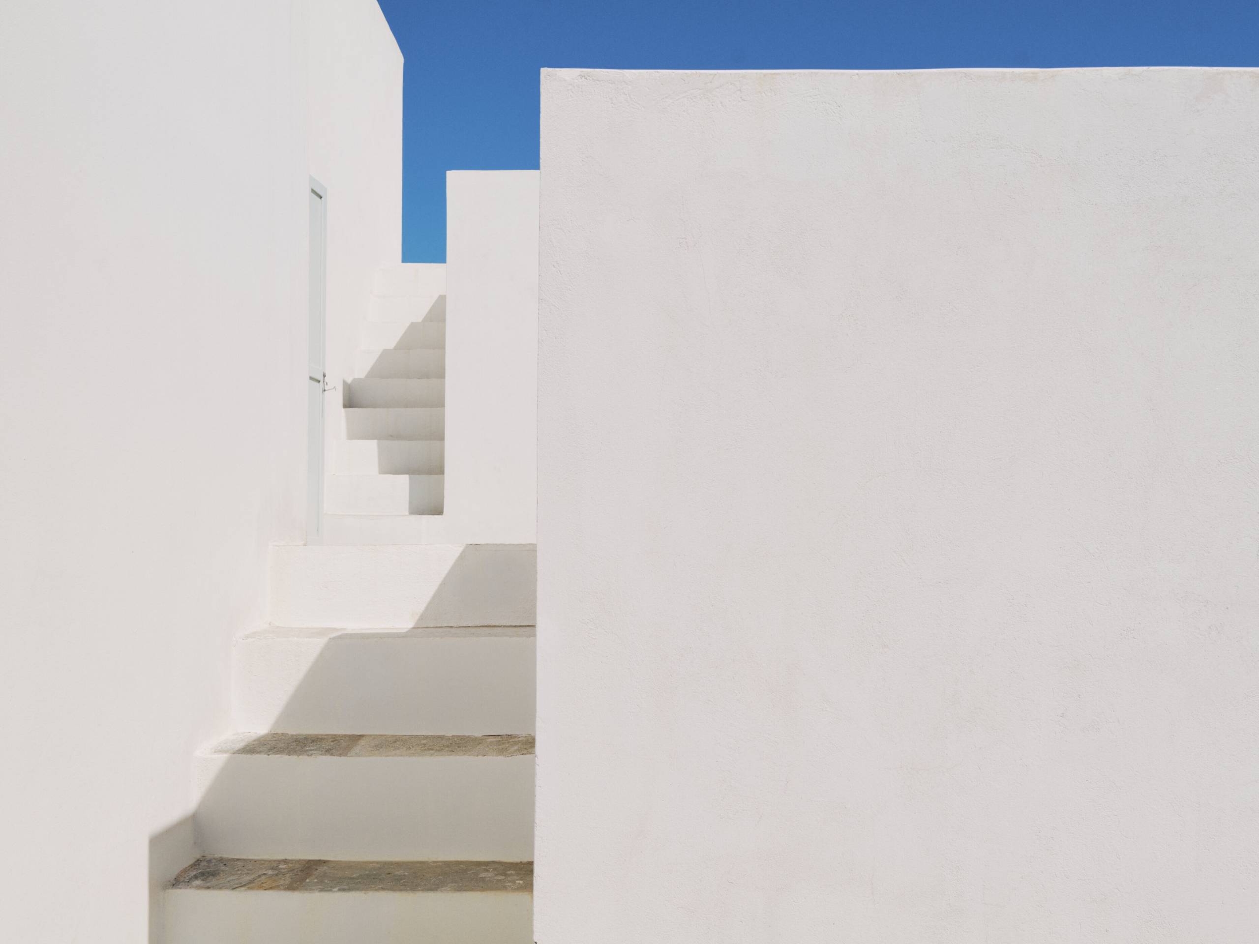 Weißes Haus vor blauem Himmel und eine weiße Treppe