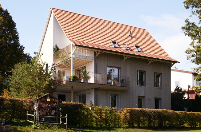 Einfamilienhaus im Grünen mit großem Parkplatz und blauem Himmel