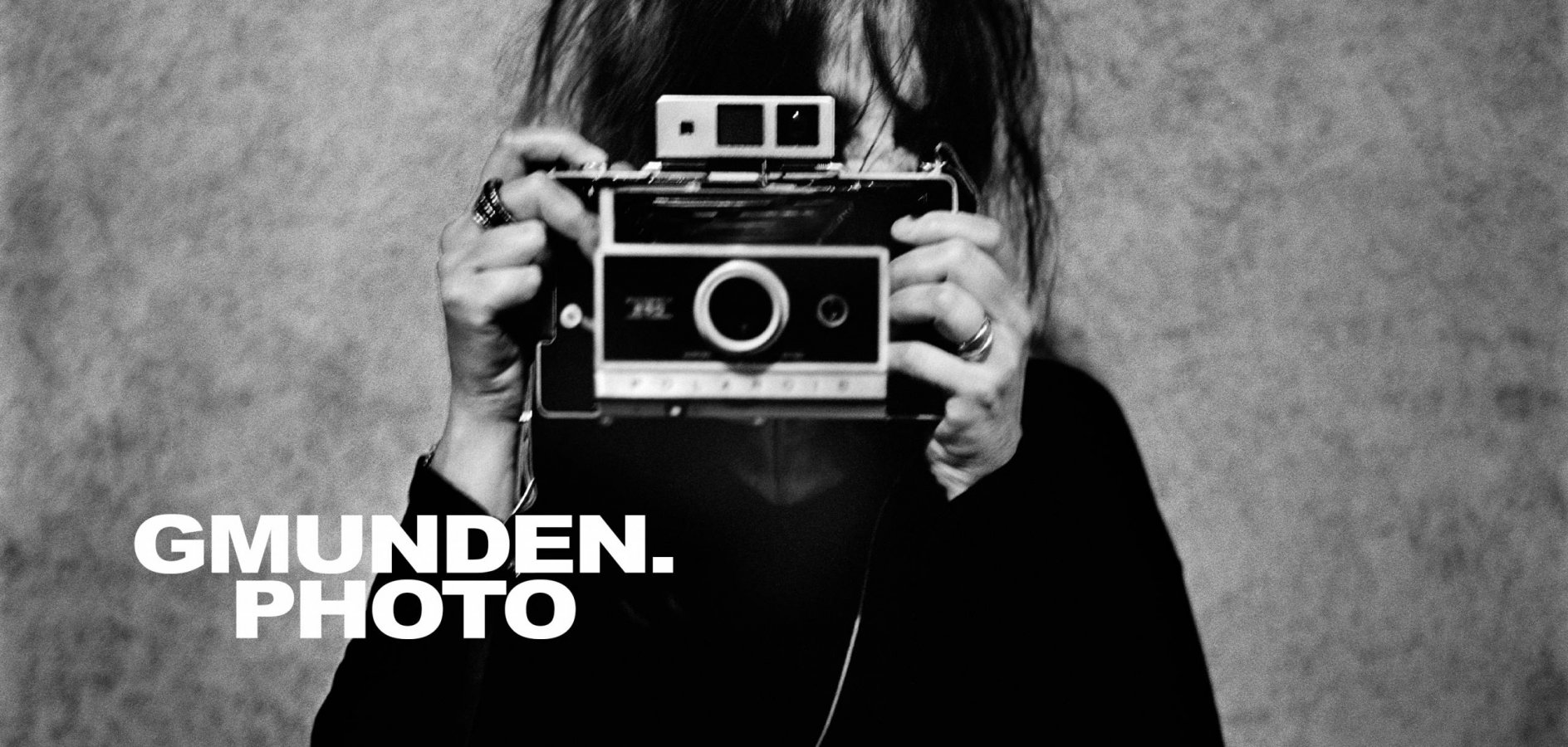 Schwarz-weißes Foto einer Frau mit alter Kamera vor dem Gesicht und Überschrift Gmunden.Photo