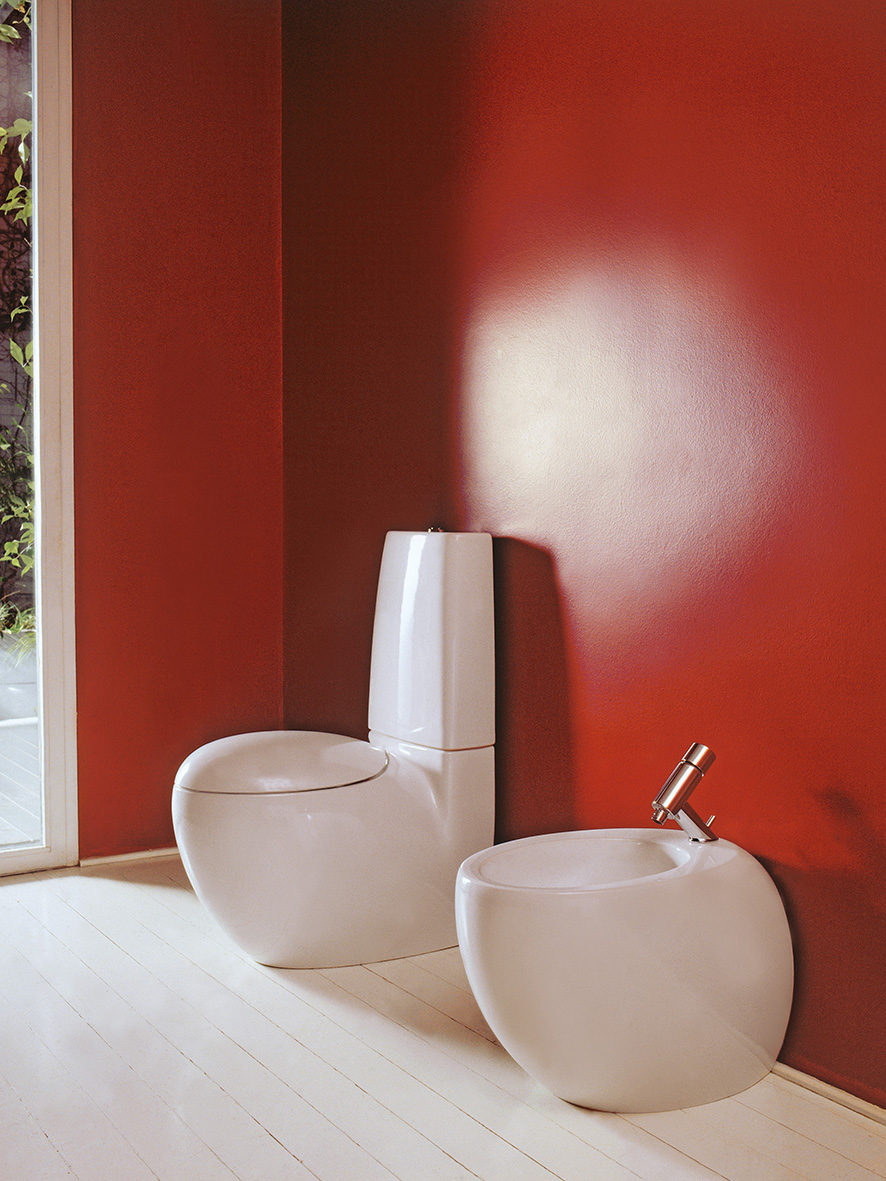 Weißes Stand-WC und Stand-Bidet vor roter Wand