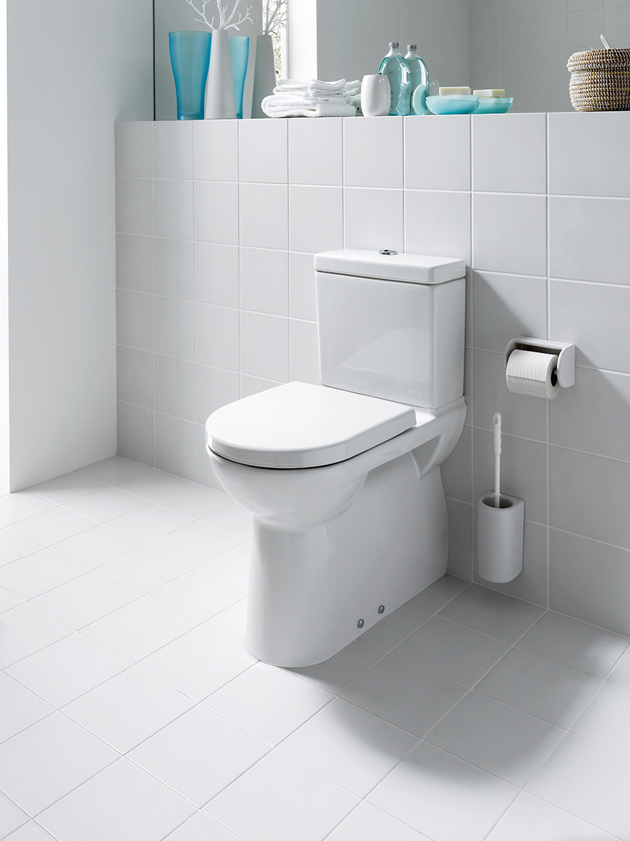 Weißes Badezimmer mit weißen Fliesen und Stand-WC mit Bürstenhalter und Toilettenpapier-Halter