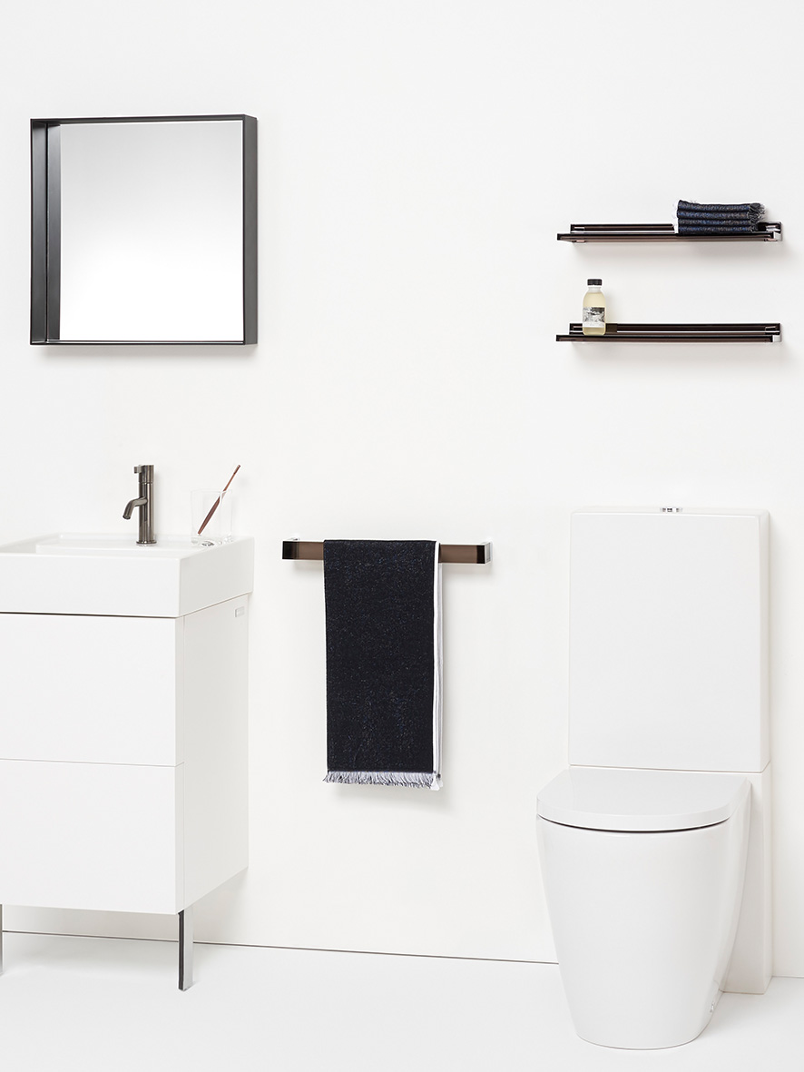 Weßes Badezimmer mit weißem Stand-WC, Waschtisch mit Möbel, gerahmtem Spiegel und schwarzes Handtuch