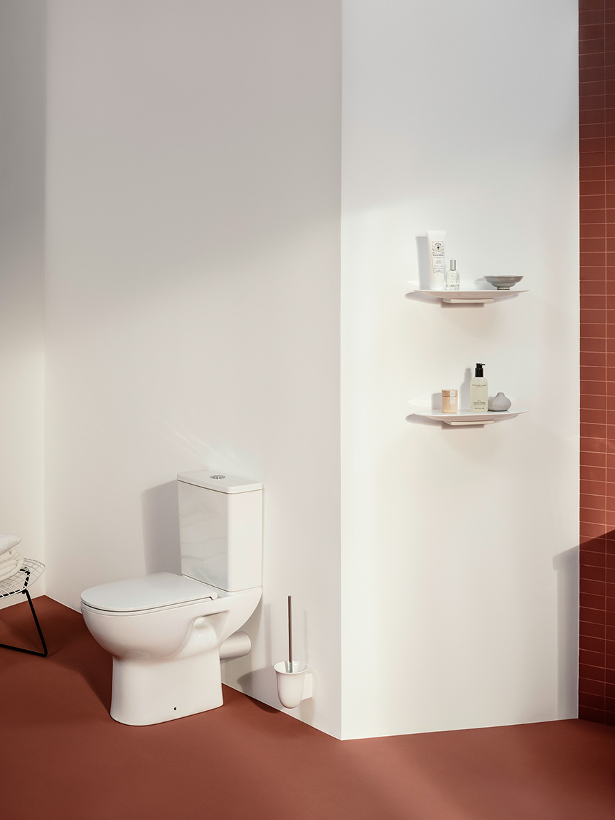 Stimmiges WC mit weißem Stand-WC, keramischen Ablagen, braun-rot farbene Fliesen 