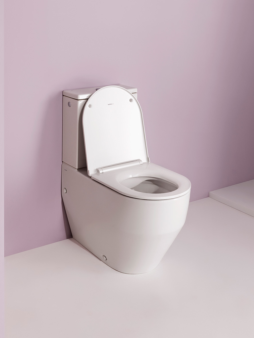 Weißes Stand WC mit offenem Deckel vor lila Wand