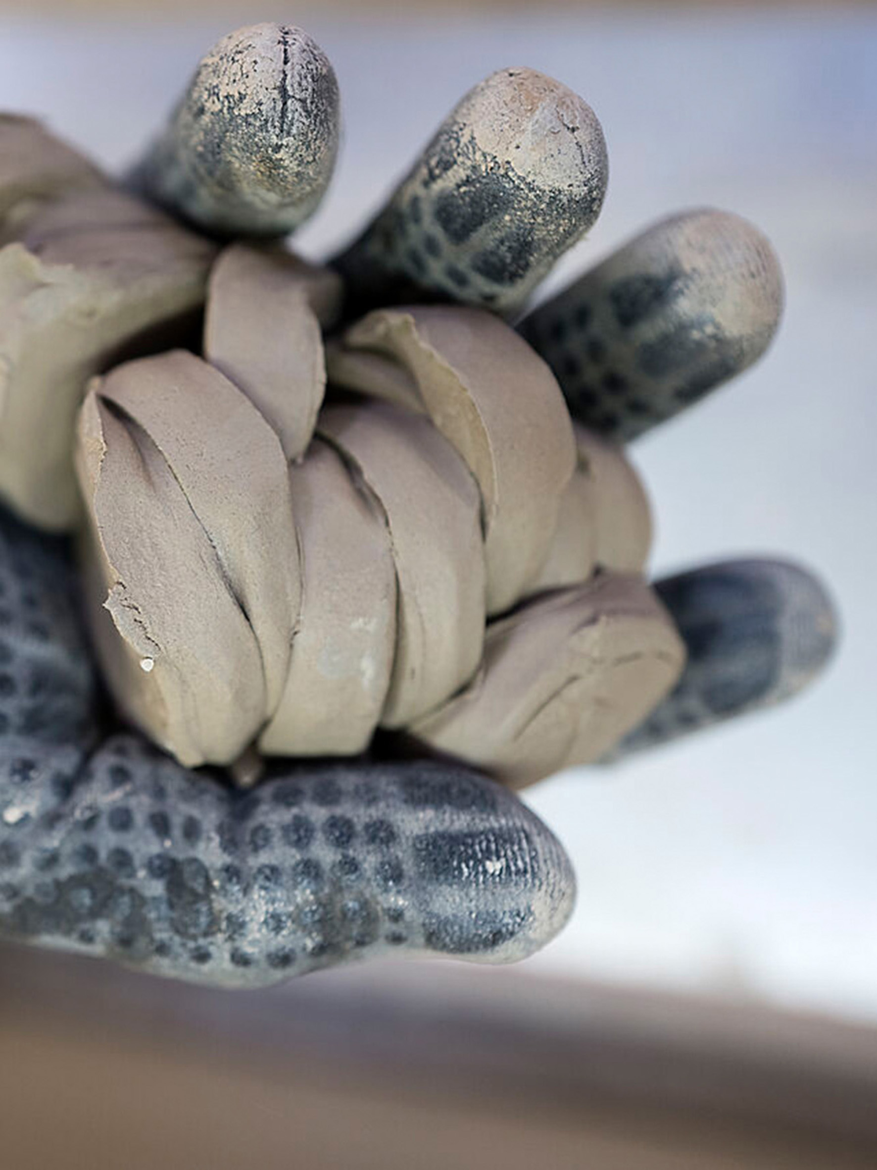 Hand in schmutzigem Hanfschuh mit abstrakt geformter Paste