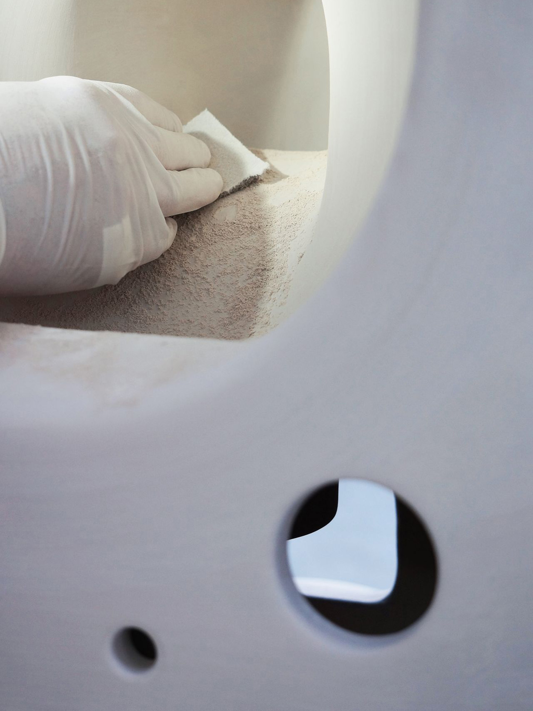 Keramische Toilette vor der Ausbrennung und Hand in Plastik Hanschuhen